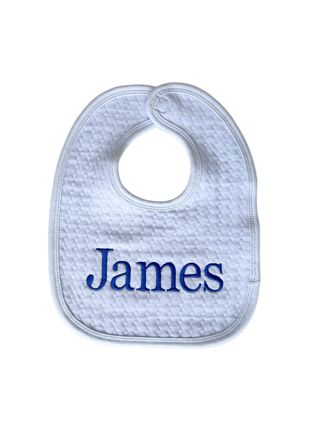 White baby bib with 'James' embroidered in blue on a light gray background