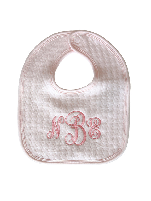 Pink baby bib with embroidered initials on a light gray background