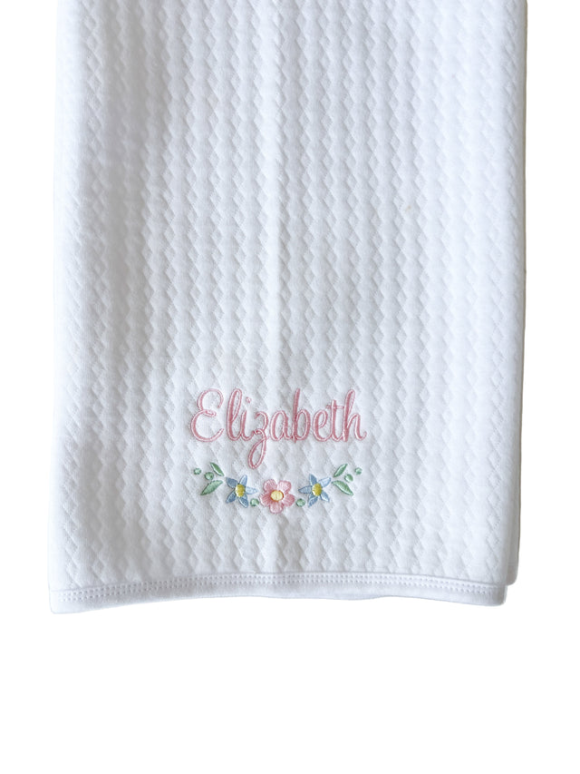 White textured towel with embroidered name 'Elizabeth' and floral design on a light gray background