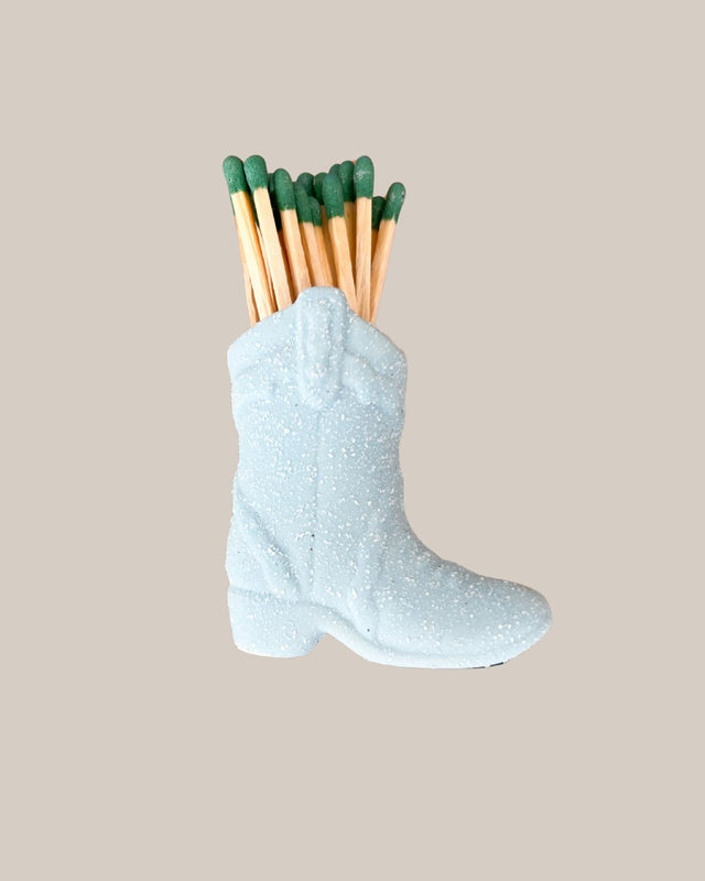 Matchbox shaped like a boot with matches on a beige background